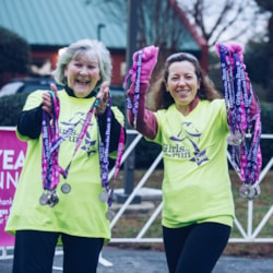 Two Girls on the Run 5k volunteers happily holding up medals